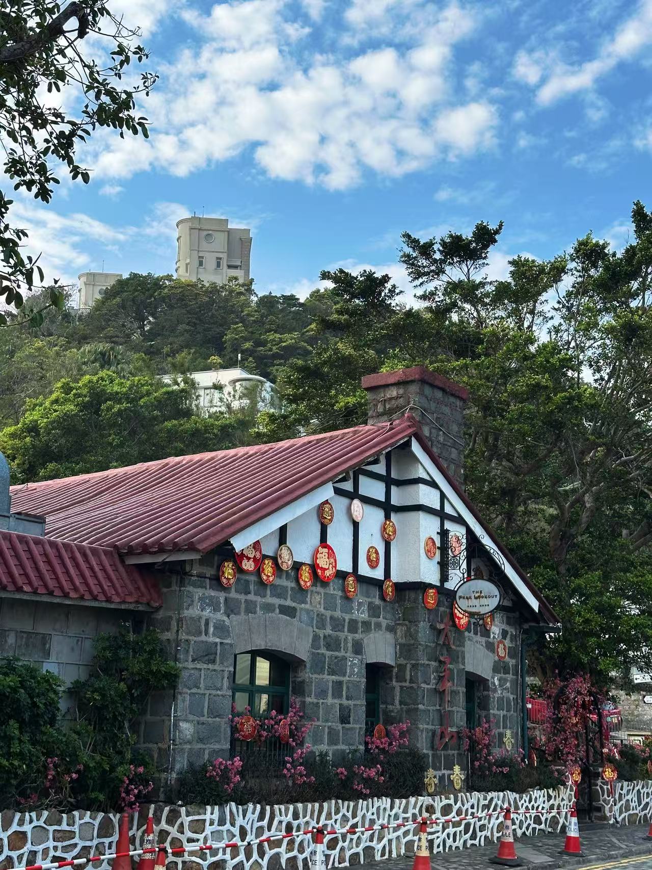 蓝天下山坡树林间的一栋石墙小屋